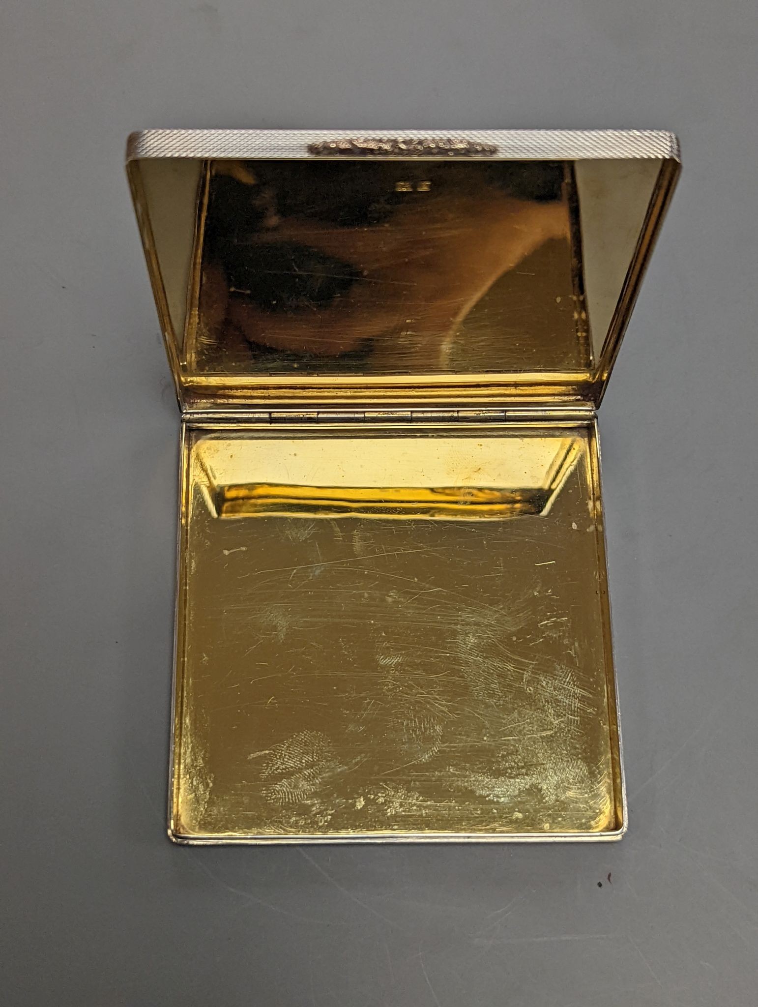 A 1960's Garrard & Co yellow metal mounted engine turned silver cigarette case, Birmingham, 1965, 88mm.